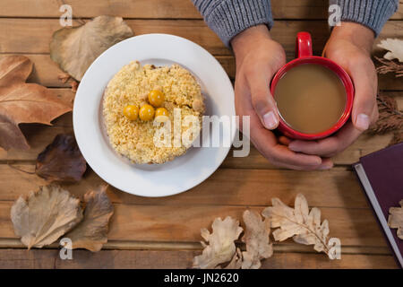 Aufwand des Mannes Hand, die Tasse Kaffee mit Frühstück und Herbst Blätter auf Tisch Stockfoto