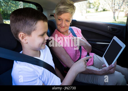 Glückliche Großmutter und Enkel mit digital-Tablette n Rücksitz des Wagens Stockfoto