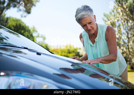 Aktive ältere Frau überprüfen ihr Auto Stockfoto