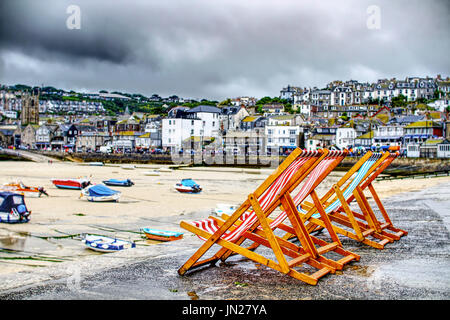 Liegestühle an einem stürmischen Sommertag in St. Ives, Cornwall Stockfoto