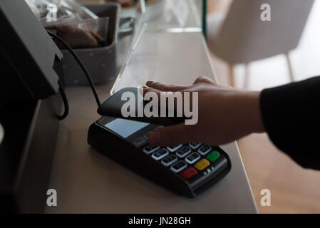 Zugeschnitten auf Kunden spielen Bill durch Smartphone an Kasse im café Stockfoto