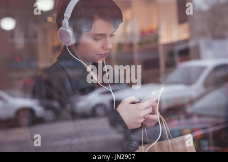 Junge Frau mit Handy im store Stockfoto