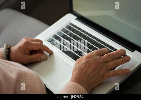 Zugeschnittenes Bild senior Frau mit Laptop zu Hause auf sofa Stockfoto