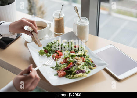 Hand auf etwas zu Essen am Tisch im Café Frau zugeschnitten Stockfoto