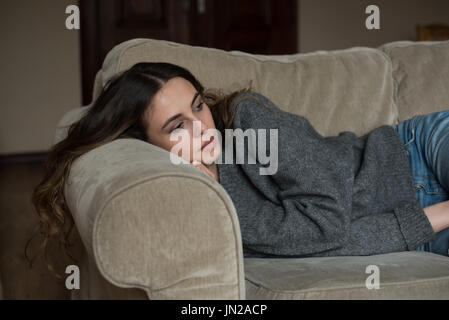Nachdenkliche Frau liegend auf dem Sofa zu Hause wegschauen Stockfoto