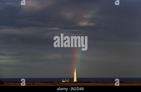 Ein Regenbogen über St Marys Leuchtturm wie die Sonne setzt in Whitley Bay. Stockfoto