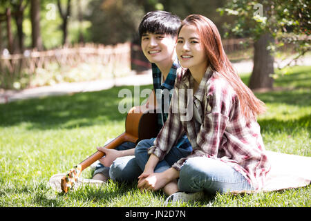 Junges Paar Gitarre spielen auf dem Rasen Stockfoto