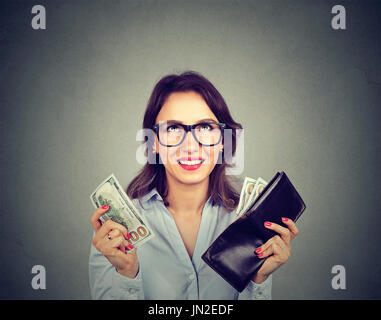 Glückliche Frau, die Geld aus der Brieftasche Stockfoto