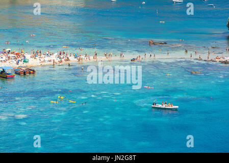 Sizilienstrand, Blick im Sommer auf Sizilianer, die sich in einer malerischen Bucht am Mazzaro Beach nahe Taormina, Sizilien, sonnen. Stockfoto