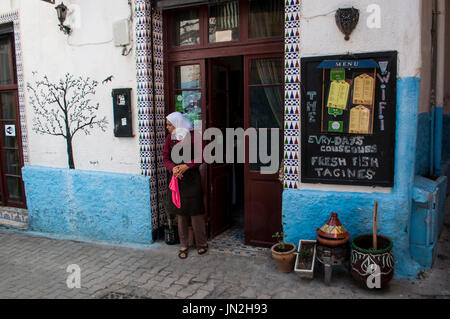 Marokko, Nordafrika: eine muslimische Frau vor einem der Restaurants des Gebiets Medina in der alten Stadt von Tanger Stockfoto