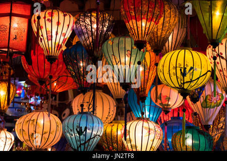 Viele Seidenlaternen aus verschiedenen Farben und designs hängen von einem Geschäft in der Nacht in Hoi an, Vietnam Stockfoto