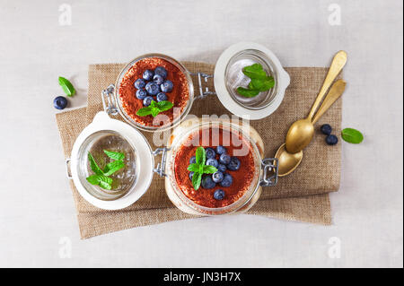 Tiramisu, traditionellen italienischen Dessert. Savoyardi Kuchen und Kaffee. auf weißen Tisch. In verschiedenen Gerichten. Bedeckt mit frischen Heidelbeeren Stockfoto