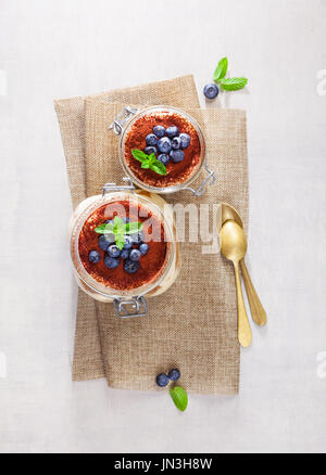 Hausgemachte Tiramisu Kuchen traditionelle italienisches Dessert im Glas auf weißem Steintisch Stockfoto