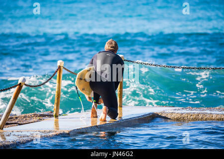 Australische Männchen tragen Surfbrett wartet darauf, geben die Brandung in Sydney, Australien Stockfoto