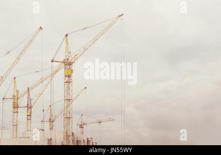 Baue ein Haus, Baustelle, Bau von Häusern, Baukräne, Baumaterial, Stadt, Tag Überdachung. Retro-getönten Foto Stockfoto