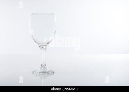 Leeres Glas reflektiert in glänzende Oberfläche vor weißem Hintergrund Stockfoto