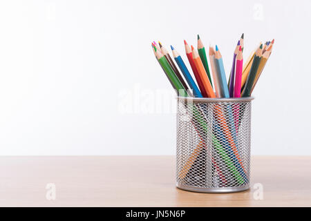 Sammlung von Buntstift Buntstifte in einem Draht mesh Container auf einem Holztisch oder Tisch mit textfreiraum an der Wand hinter Stockfoto