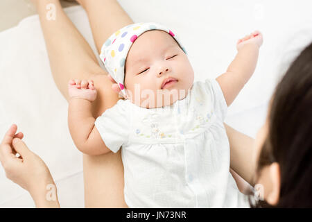 Porträt von adorable Baby schläft auf Mutter Bein Stockfoto