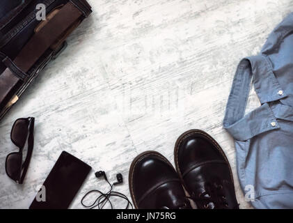 Herren Kleidung und Accessoires. Jeans, Schuhe, Brillen, Smartphone auf hölzernen Hintergrund. Draufsicht mit Textfreiraum Stockfoto