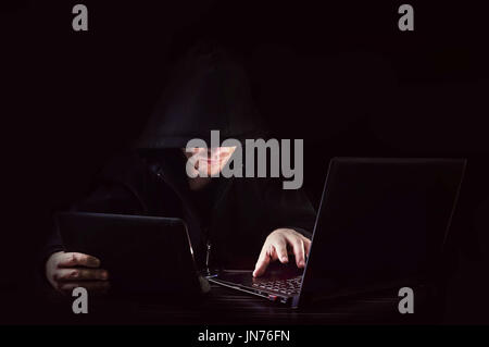 Hacker ein Tablet und ein Computer auf schwarzem Hintergrund Stockfoto