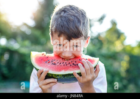 Glückliche kleine kaukasischen junge mit Lächeln Biss in Wassermelone im freien Stockfoto