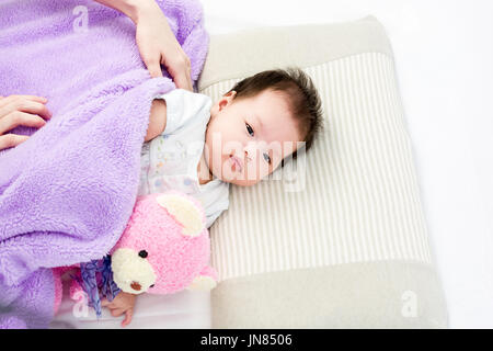 Porträt des schlafenden Babys auf einem Bett liegend mit Bär Puppe Stockfoto