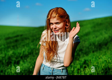 Schöne Frau in der Natur versucht, jemand zu verstehen, indem Sie versuchen, etwas mit dem setzen ihre Hand in ihren Ohren zu hören. Stockfoto