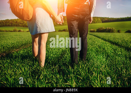 Junges Paar wird durch die Greenfield bummeln. Frau und Mann halten einander die Hände. Stockfoto