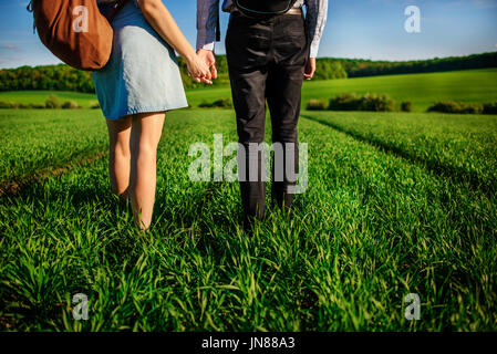 Junges Paar wird durch die Greenfield bummeln. Frau und Mann halten einander die Hände. Stockfoto