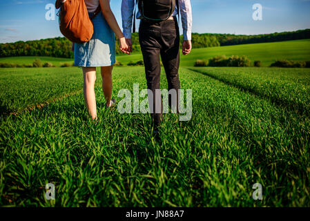 Junges Paar wird durch die Greenfield bummeln. Frau und Mann halten einander die Hände. Stockfoto