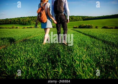 Junges Paar wird durch die Greenfield bummeln. Frau und Mann halten einander die Hände. Stockfoto