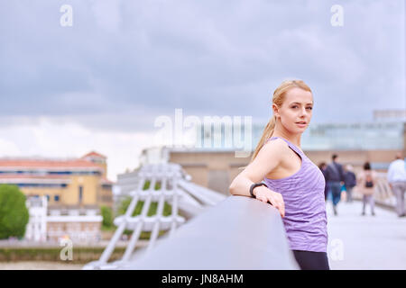 Eine junge Frau hält zur Entspannung während des Trainings in der Stadt Stockfoto