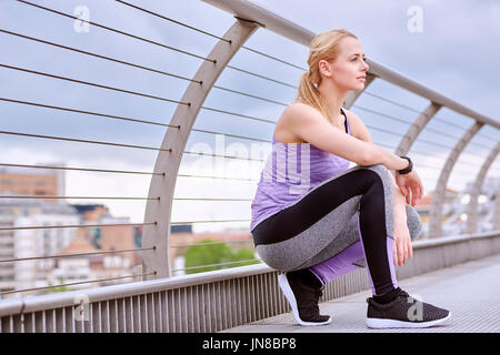 Eine junge Frau hält zur Entspannung während des Trainings in der Stadt Stockfoto