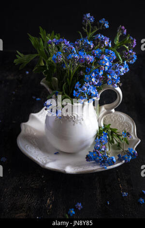 Sommer Blumen Tischdekoration mit leuchtend blauen Vergissmeinnicht Blumen auf Holztisch Stockfoto