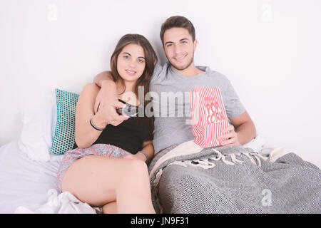 Junges Paar Filme schauen im Bett und Essen Popcorn. Im Innenbereich. Stockfoto