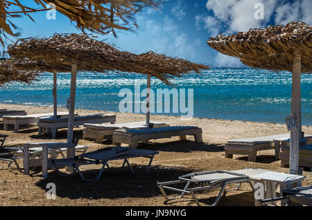 Insel Paros, Kykladen, Griechenland. Stroh Sonnenschirme und Strand liegen am Golden Beach. Stockfoto