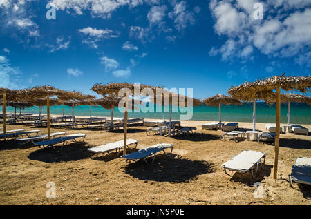 Insel Paros, Kykladen, Griechenland. Stroh Sonnenschirme und Strand liegen am Golden Beach. Stockfoto