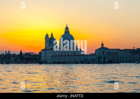 Venedig, Veneto, Italien. Dramatische orange Sonnenuntergang über Basilica di Santa Maria della Salute und des Punta della Dogona, Dorsuduro, Venedig in t Stockfoto