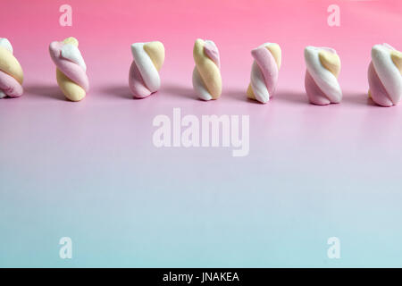 Regenbogen Marshmallow Multi farbige Süßigkeiten Süßigkeiten auf einem Farbverlauf Hintergrund rosa und blau. Minimale Farbe Still Life Fotografie Stockfoto