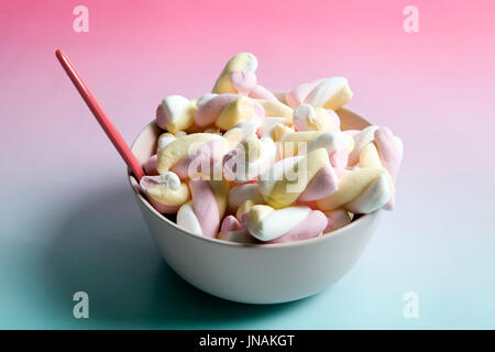 Regenbogen Marshmallow Multi farbige Süßigkeiten Süßigkeiten auf einem Farbverlauf Hintergrund rosa und blau. Minimale Farbe Still Life Fotografie Stockfoto