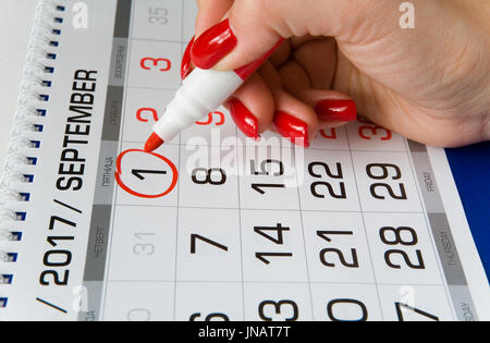 Der Kalender. Eine schöne weibliche Hand markiert das Datum am 1. September mit einem Marker. Stockfoto