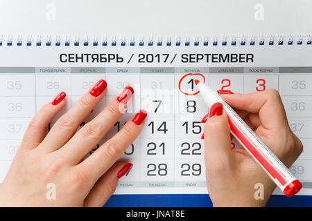 Der Kalender. Eine schöne weibliche Hand markiert das Datum am 1. September mit einem Marker. Stockfoto