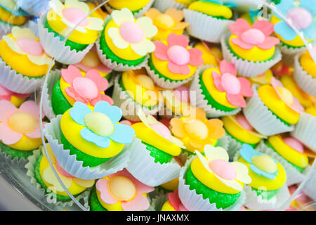 Haufen von bunten hausgemachte Kuchen in Papierkörbe mit Blume geformt Dekorationen Stockfoto