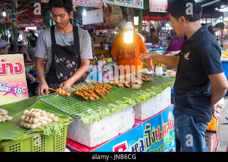 Mann kaufen Fleischspieße an Chatuchak Market, Bangkok, Thailand Stockfoto