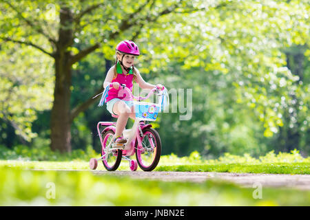 Kinder Reiten Fahrrad. Kind auf dem Fahrrad im sonnigen Park. Kleine Mädchen genießen Radtour auf dem Weg zur Schule an warmen Sommertag. Vorschüler lernen, balan Stockfoto