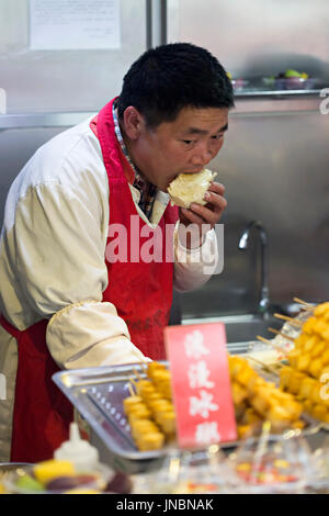 Chinesischen Verkäufer auf traditionellen Lebensmittelmarkt Sandwich zu essen. Wangfujing, Chaoyang District, Beijing, China, 5. April 2016 Stockfoto