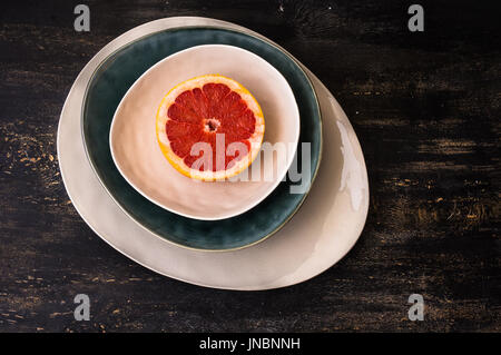 Hellen Bio Grapefruit Slice auf rustikale Platten auf dunklen Holztisch mit Exemplar Stockfoto