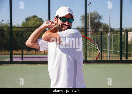 Profi-Tennisspielerin mit Gesicht Aufwand einen Tennis-Kick mit dem Schläger auf einem Tennisplatz an einem sonnigen Tag zu tun. Stockfoto