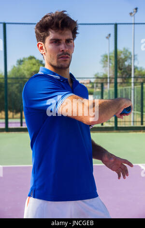 Profi-Tennisspieler tut ein Kick-Tennis auf dem Tennisplatz an einem sonnigen Sommermorgen. Das ist in der Sportswear gekleidet. Stockfoto