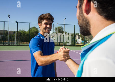 Zwei Männer, professioneller Tennisspieler Hände schütteln vor und nach dem Tennismatch. Beide lachen, sind sie glücklich. Sie sind Freunde. Stockfoto